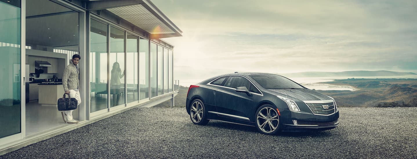 A used Cadillac ELR is parked in a driveway next to a house on a rainy day in Fort Worth, TX.