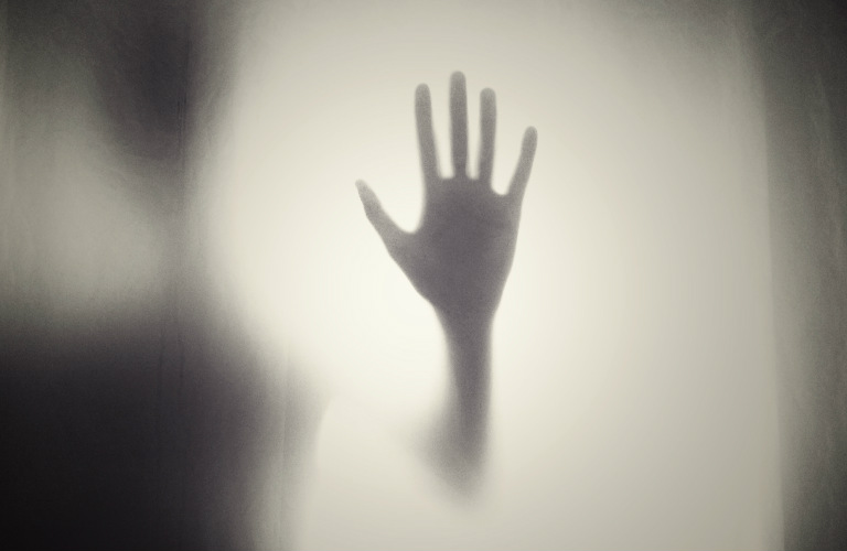 picture of a ghostly hand pressing on a window